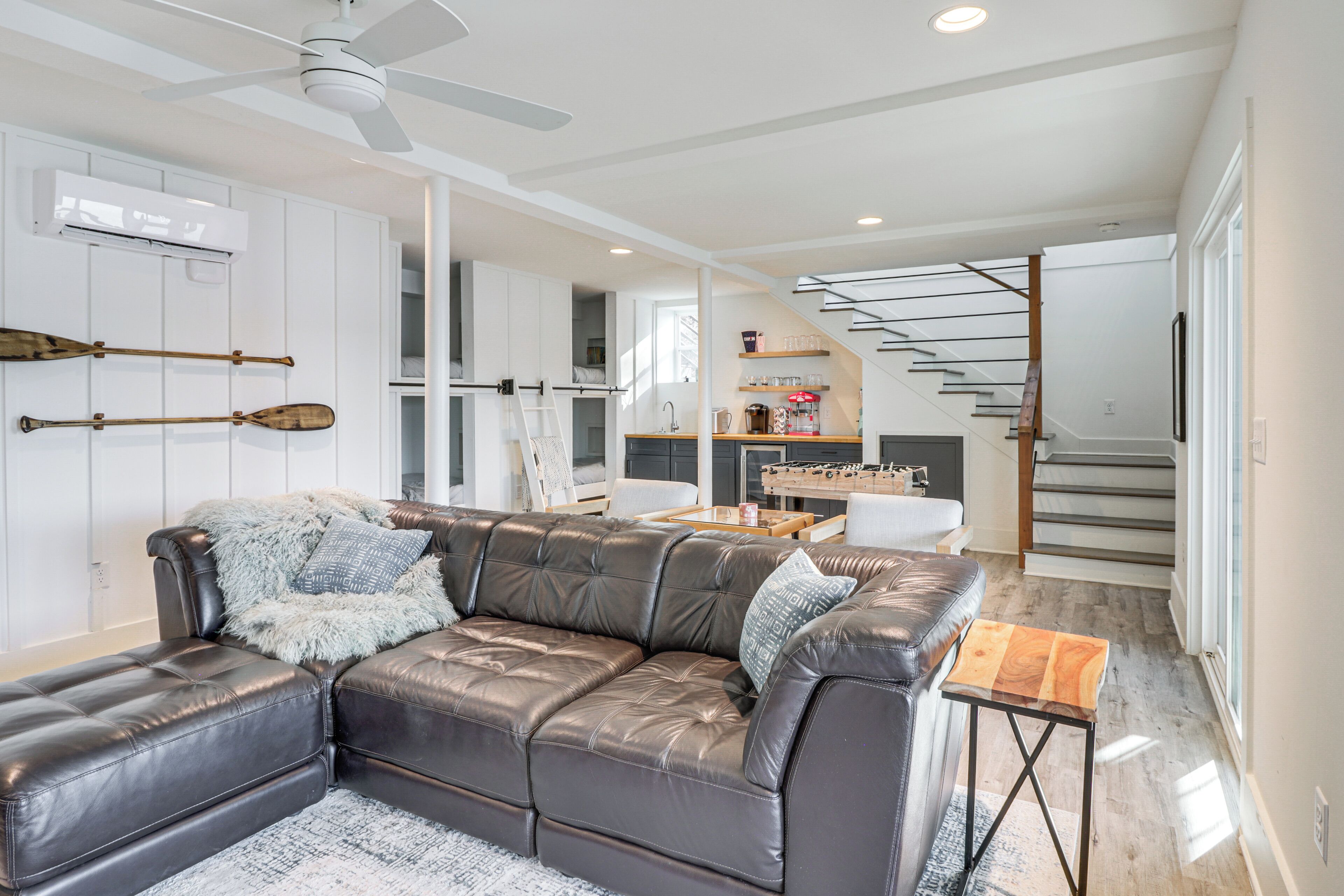 A modern living room with a leather sectional sofa, a small wooden coffee table, and a staircase leading to an upper level.