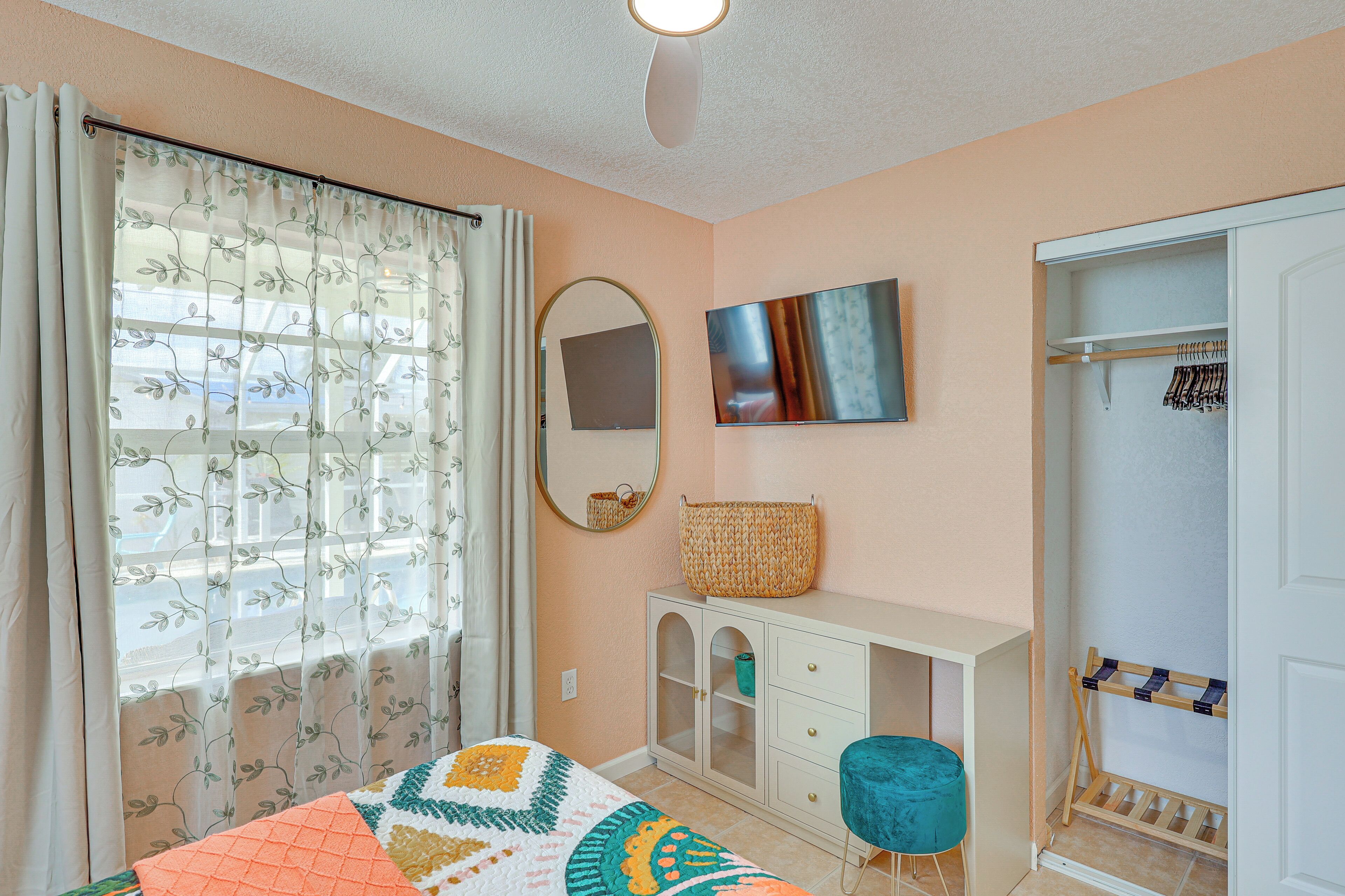 Un dormitorio con cama, armario, espejo y televisor.