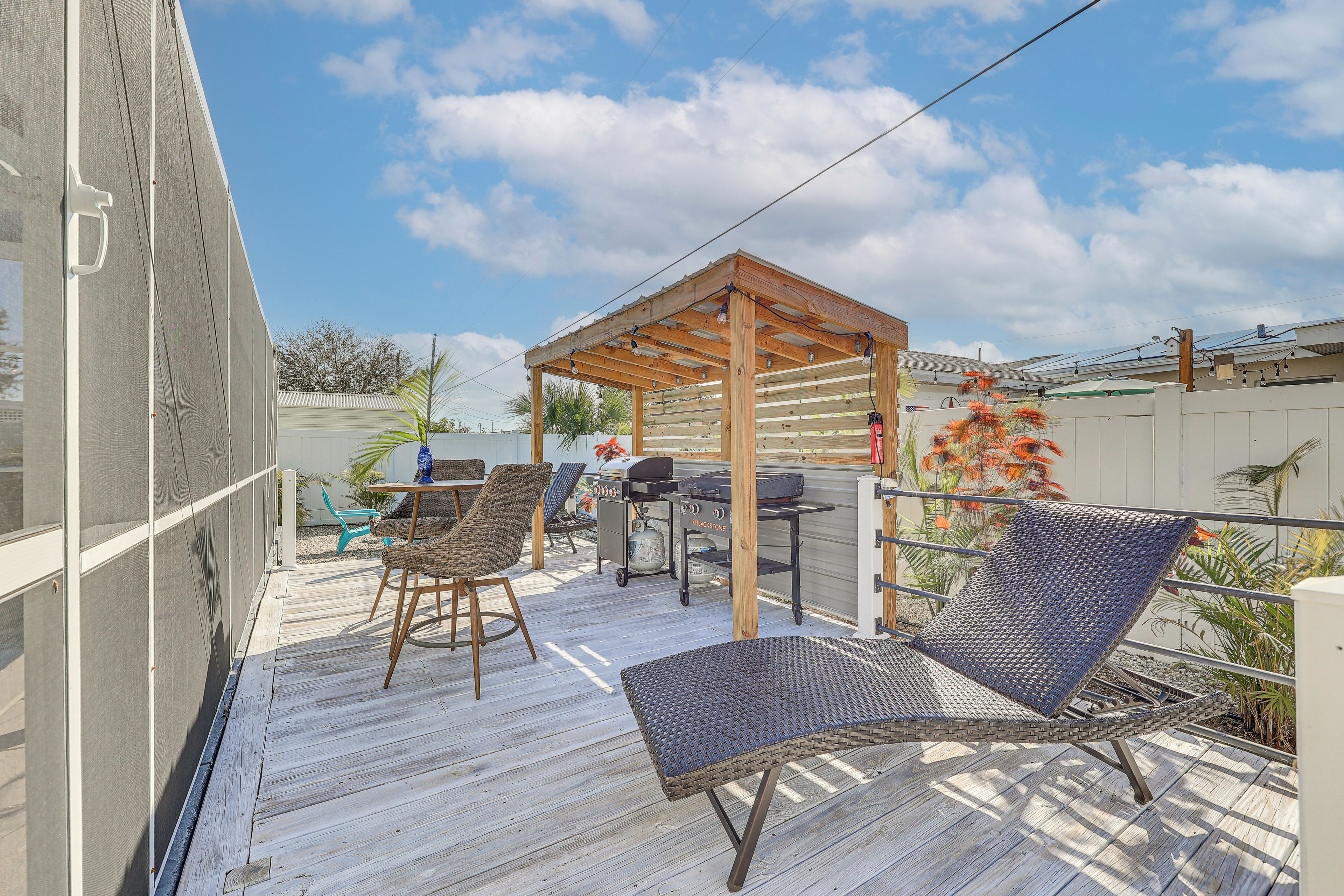 A wooden deck with outdoor furniture, a grill, and a pergola.