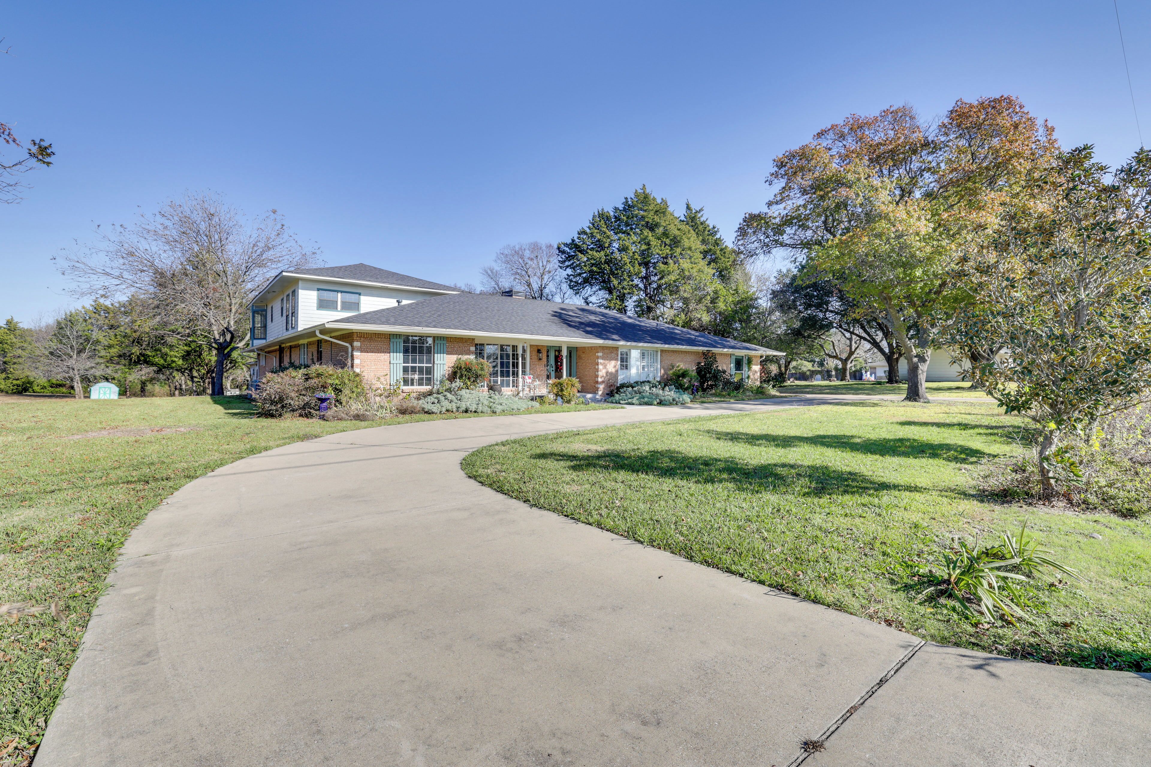 A two-story house with a curved driveway leading to a front door.
