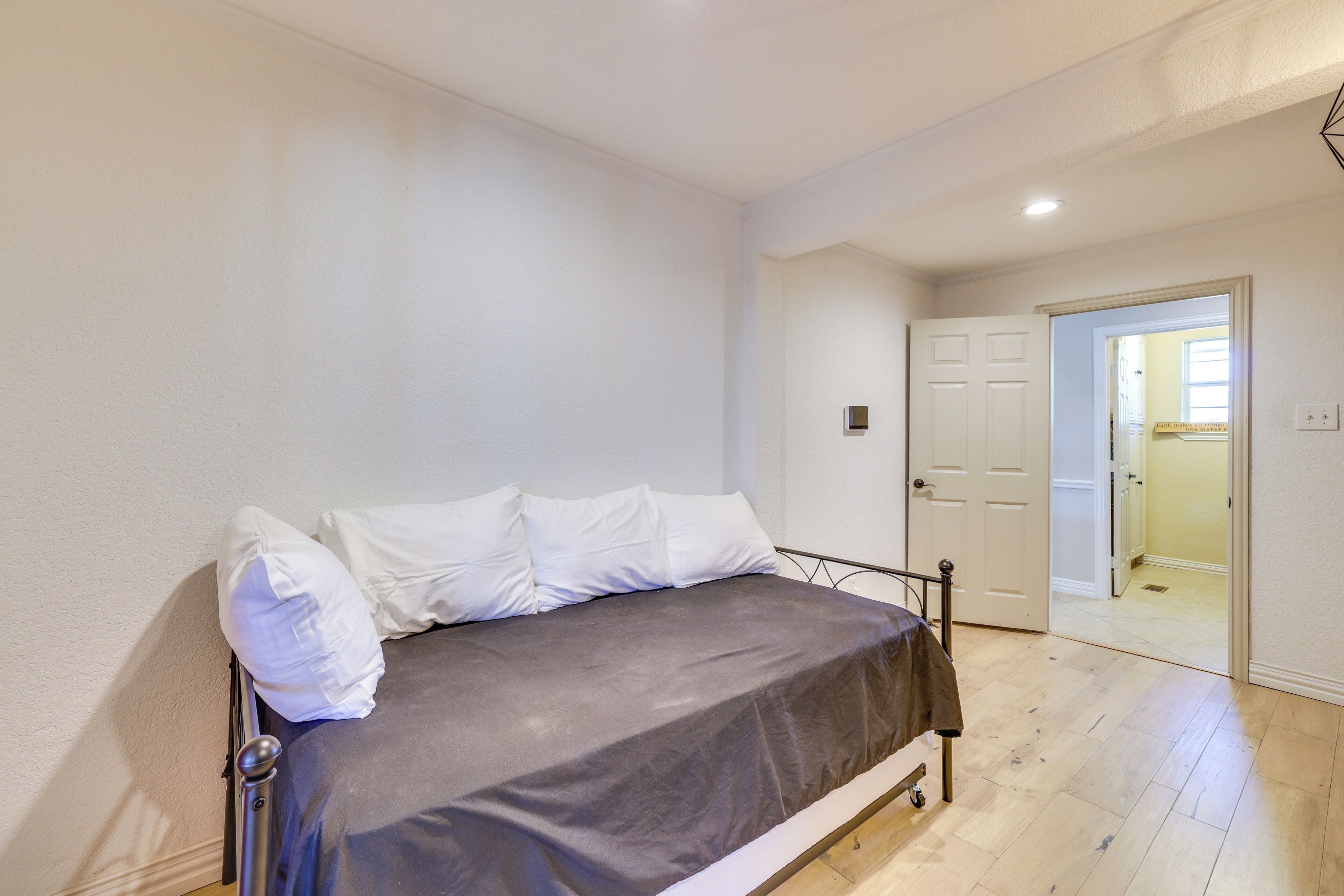 Un dormitorio con cama, paredes blancas y suelo de madera.