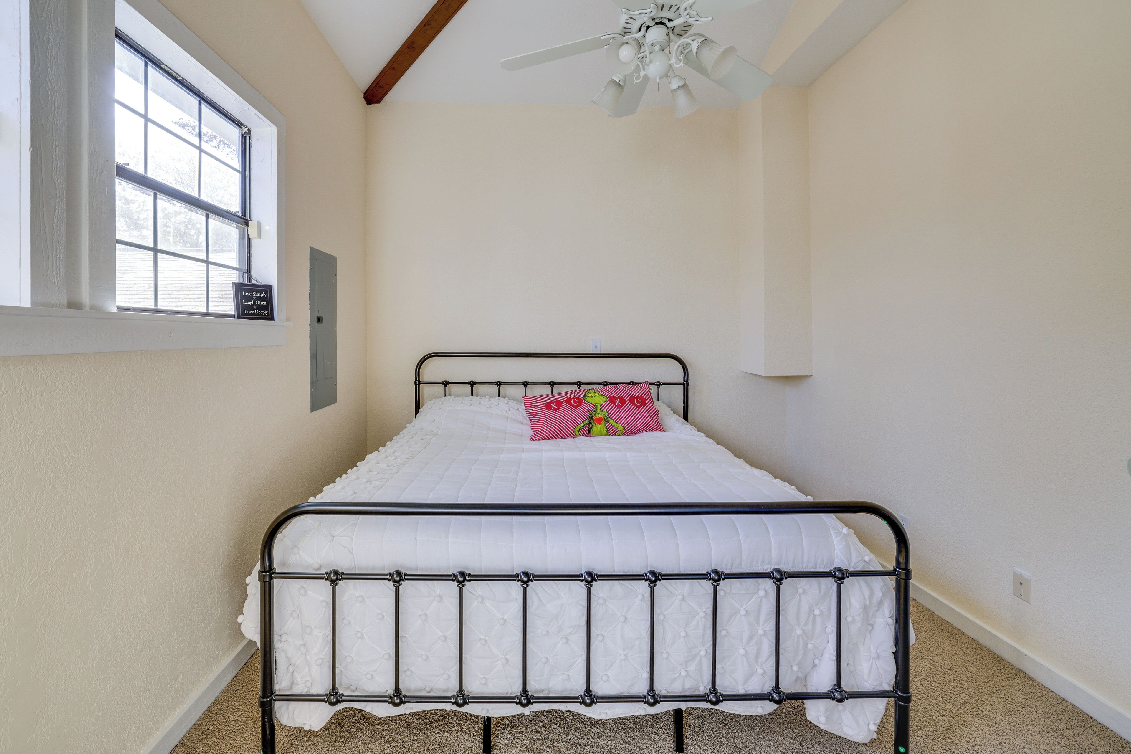 A bedroom with a bed, a window, and a ceiling fan.