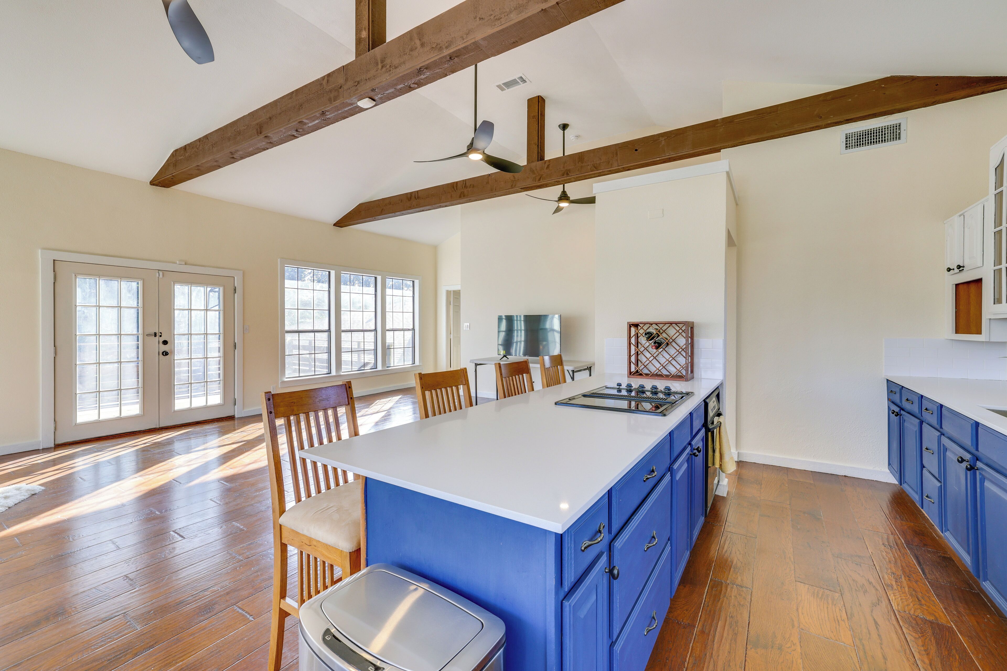 Una cocina amplia con vigas de madera, una isla grande y armarios azules.