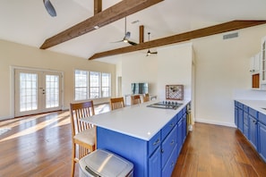 A spacious kitchen with a large island, wooden beams, and a view to the dining area.
