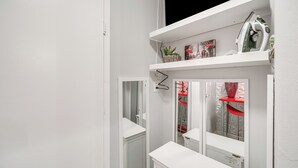 A white interior with a built-in shelving unit, a small plant, and a red chair. - 6 Mi to Downtown Cleveland: Lakeview Condo! (Lakewood)