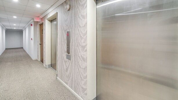 A hallway with a patterned carpet, a marble wall, and an elevator. - 6 Mi to Downtown Cleveland: Lakeview Condo! (Lakewood)