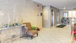 A lobby with a reception desk, a patterned armchair, and a potted plant. - 6 Mi to Downtown Cleveland: Lakeview Condo! (Lakewood)