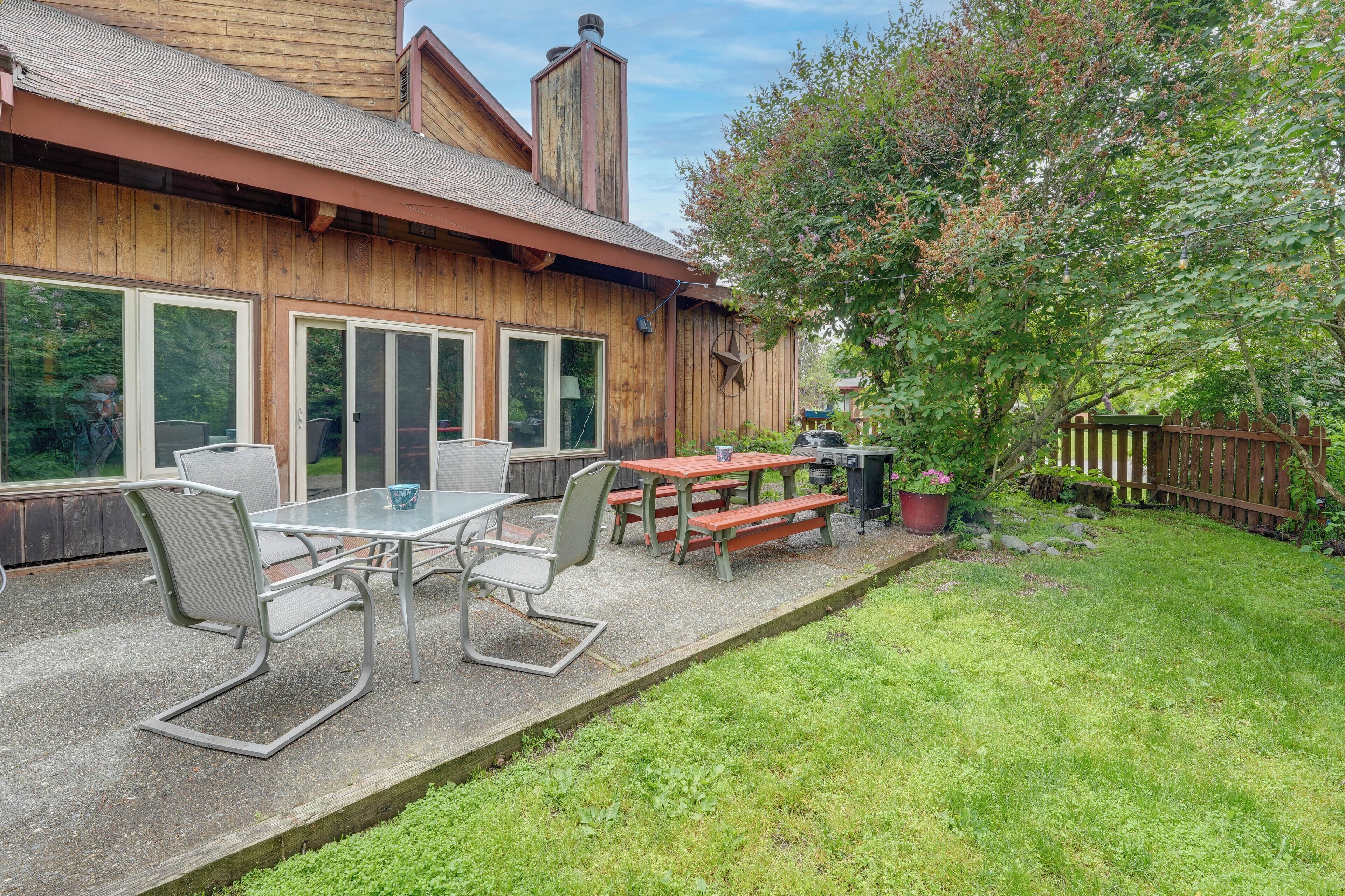 Une terrasse en bois avec des meubles d’extérieur, un barbecue et un grand arbre.