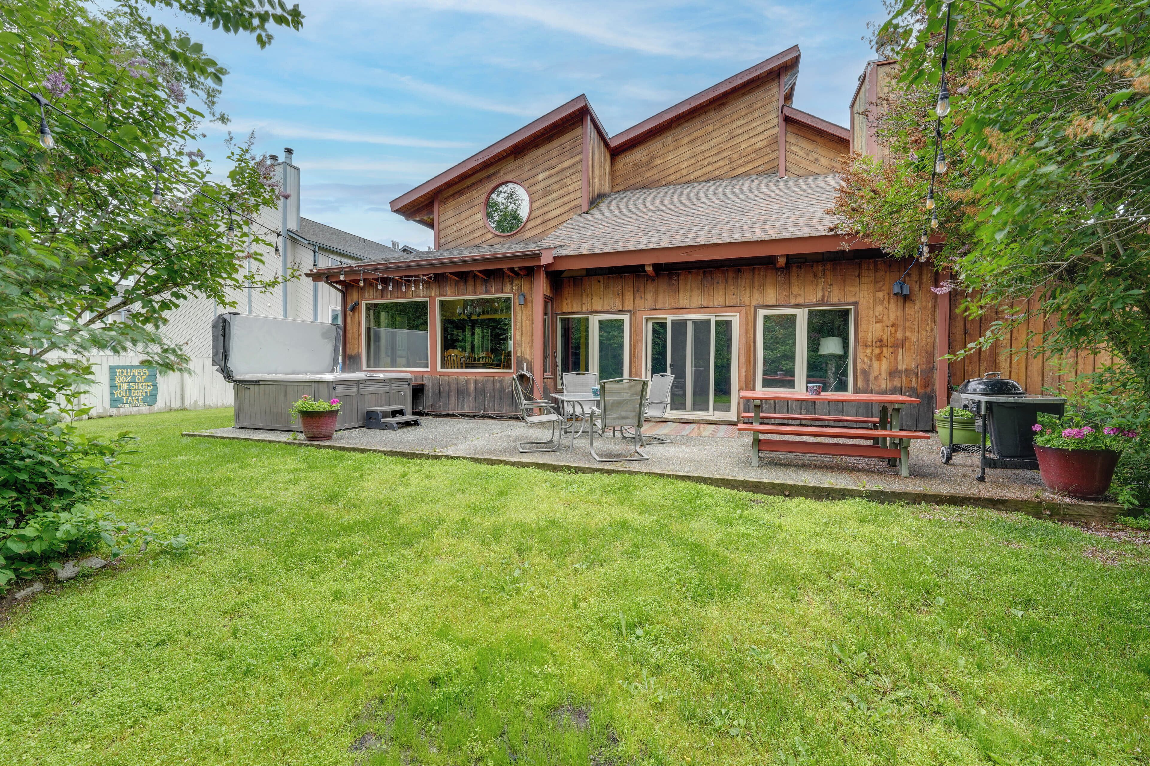 A wooden building with a patio area, outdoor seating, and a grill.