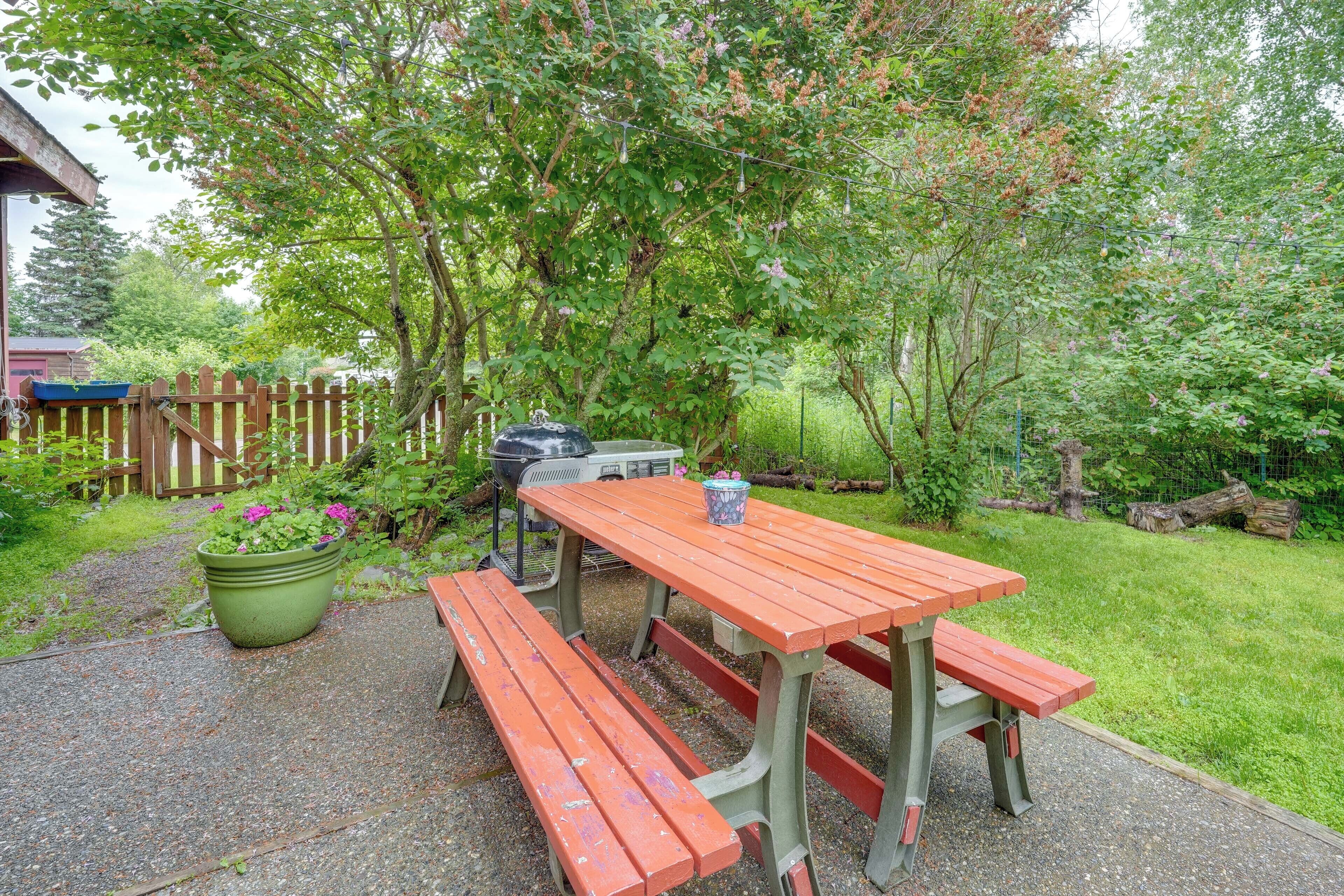 A picnic table with benches, a barbecue grill, and a potted plant.