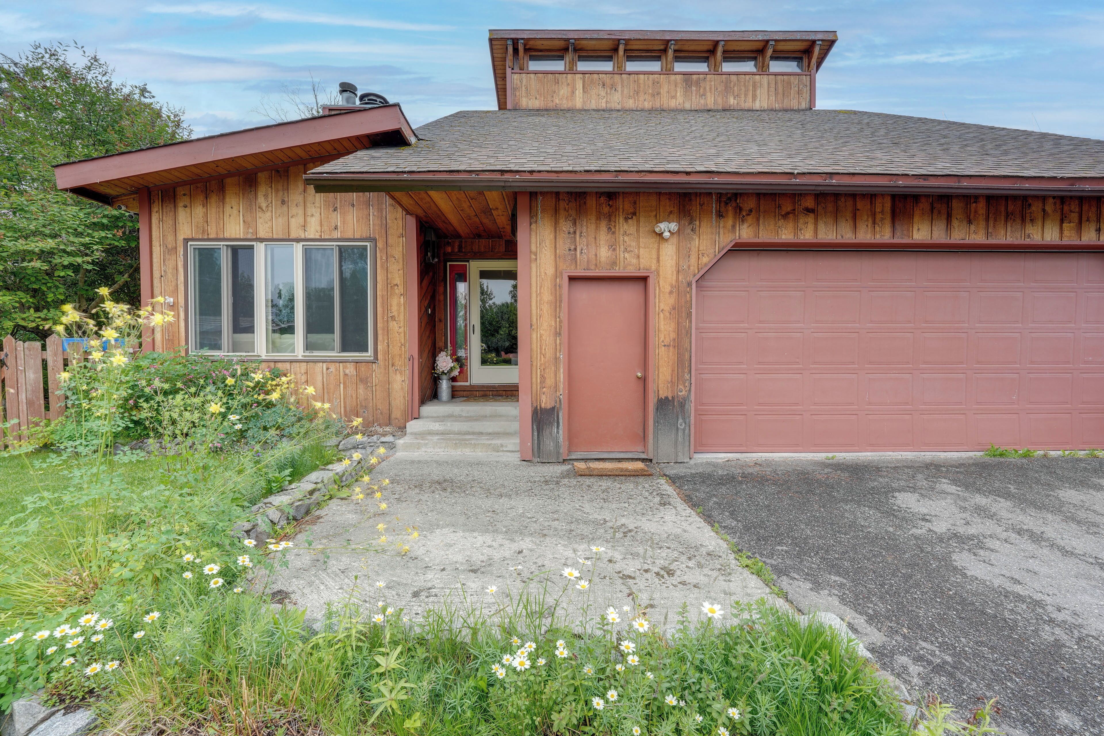 A wooden house with a garage, a front door, and a small porch area.
