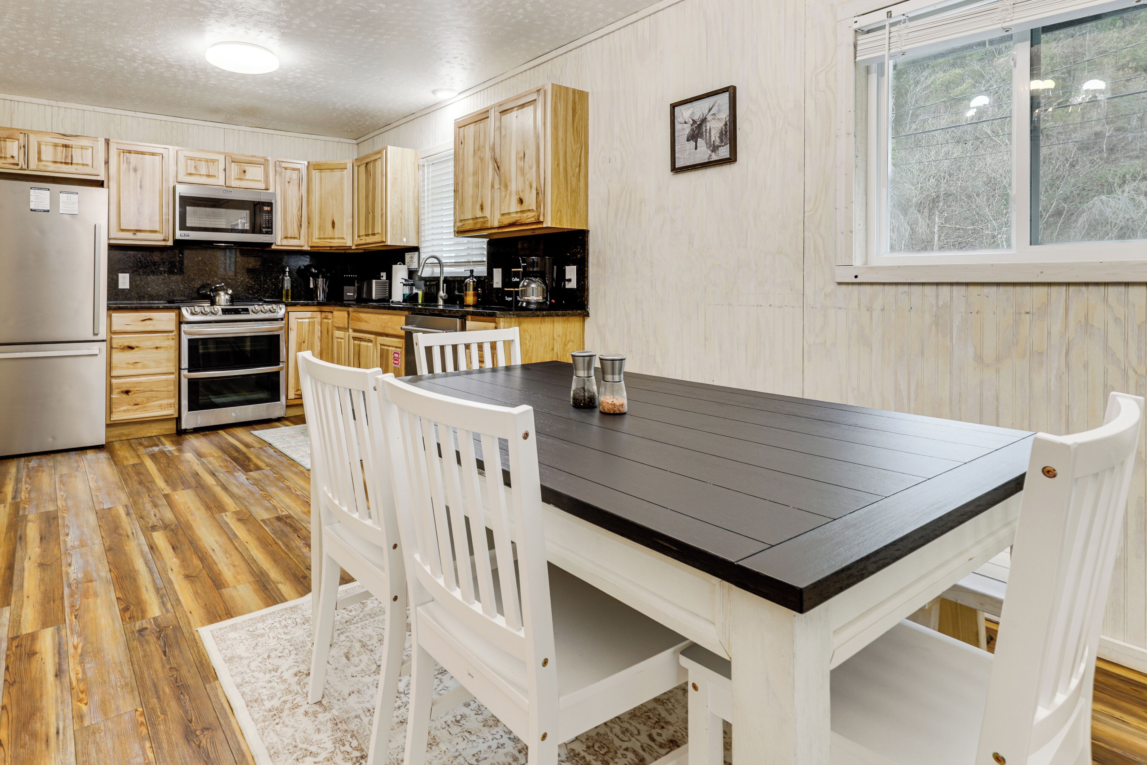 A kitchen with wooden cabinets, a black countertop, and white chairs.
