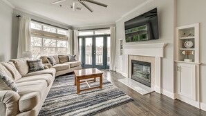 Un salon comprenant un canapé, une table basse, une cheminée, un téléviseur et un ventilateur de plafond.