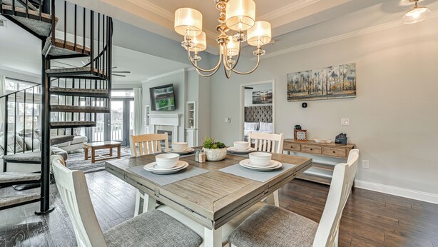 Un coin repas avec une table en bois, des chaises blanches et un lustre.