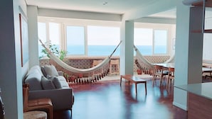 A spacious living area with a hammock, a sofa, and a dining table. - COBAR0108 - Edifício Oceania (Salvador)