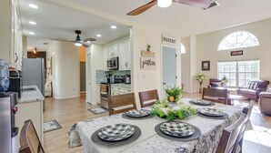 A dining area with a table set for six, kitchen in the background, and a ceiling fan. - Outdoor Kitchen & Gaming Garage: Bradenton Retreat (Bradenton)