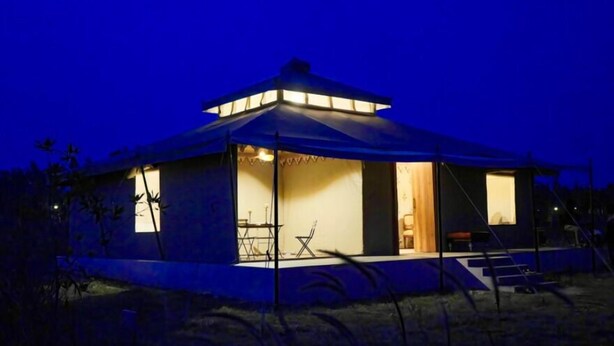 A single-story, A-frame structure with a covered patio area, a visible staircase, and a door leading to an interior space.