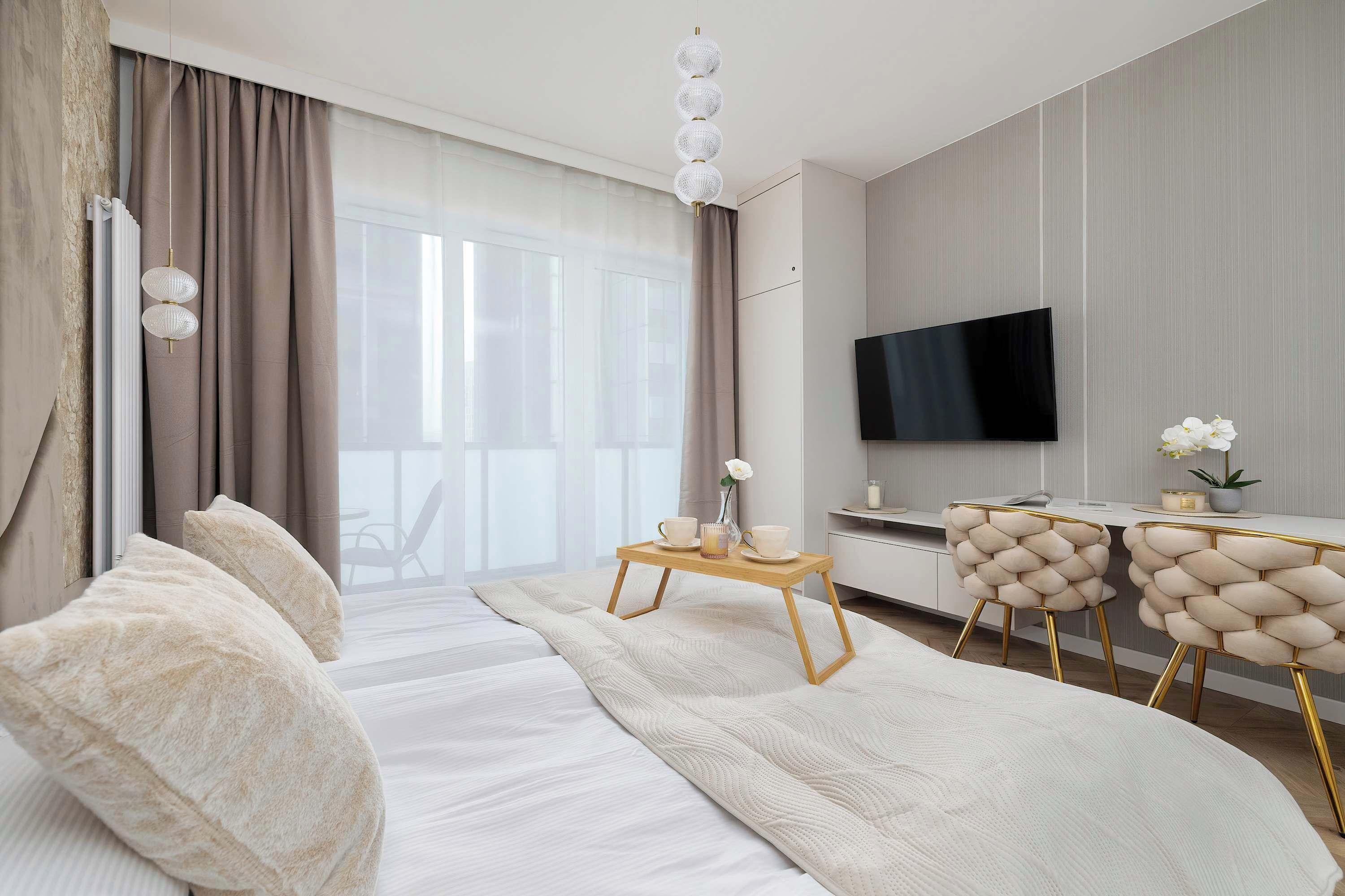 Une chambre d’hôtel moderne dotée d’un grand lit, d’un bureau avec des chaises, d’une télévision à écran plat et offrant une vue sur l’extérieur.
