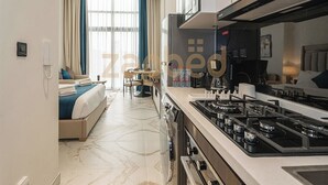 Ein modernes Hotelzimmer mit Küchenzeile, Esstisch und Bett.
