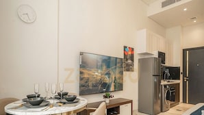 Ein modernes Wohnzimmer mit Essbereich, Flachbildfernseher, Küche und einem Bett.