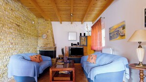 A living room with two blue sofas, a wooden coffee table, a fireplace, a television, and a painting on the wall.