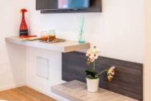 A modern room with a flat-screen TV mounted on the wall, a small white table with a potted plant, and a wooden floor. - GuestHost - Spacious room with balcony that can accommodate up to 4 people, located in a convenient and central position, in a building with concierge. The accommodation is located just 10 minutes walk from the historic center, in an area equipped with e (Bari)