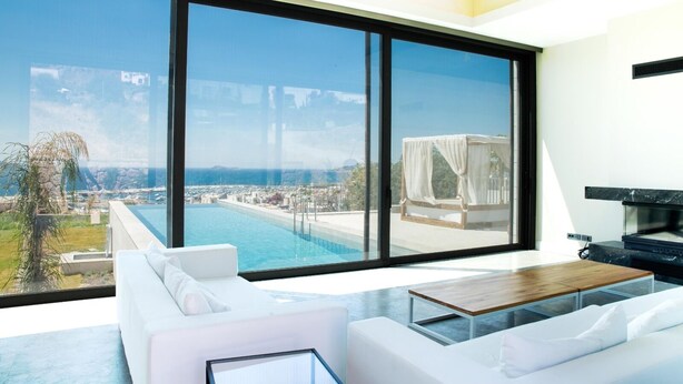 Un salon moderne doté d’une grande baie vitrée, d’une piscine et d’un lit à baldaquin.