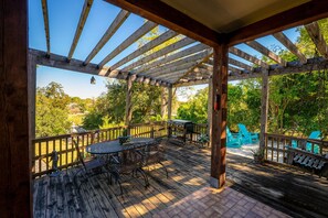 Eine Holzterrasse mit einer Pergola, Sitzgelegenheiten im Freien und einem Grillbereich.
