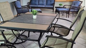 Een terras met een tafel en stoelen, een bank en een kleine plant op de tafel.