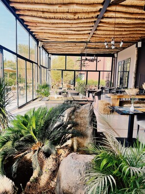 A spacious indoor area with large windows, a thatched roof, and various seating arrangements. - 5 bedroom luxury villa located in grounds of luxury Resort Hotel (Marrakech)