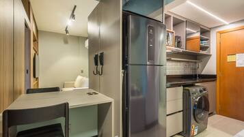 Una cocina compacta con refrigerador, lavadora y un pequeño comedor.
