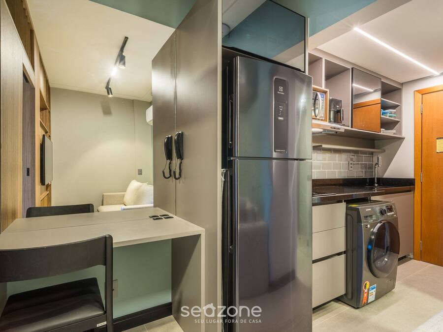 Una cocina compacta con refrigerador, lavadora y un pequeño comedor.