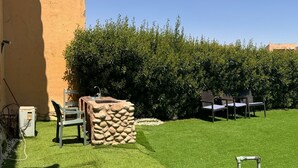 Une terrasse avec une table en pierre, deux chaises et un petit évier.