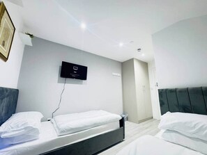 Ett modernt hotellrum med två sängar, en platt-TV som är monterad på väggen och en dörr som leder till badrummet.