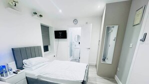A modern hotel room with a large bed, bedside tables, a TV, and a mirror. - Modern Twin En-Suite close to Cardiff Centre (Cardiff)
