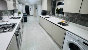 A modern kitchen with a central island, built-in appliances, and a dishwasher. - Modern Twin En-Suite close to Cardiff Centre (Cardiff)