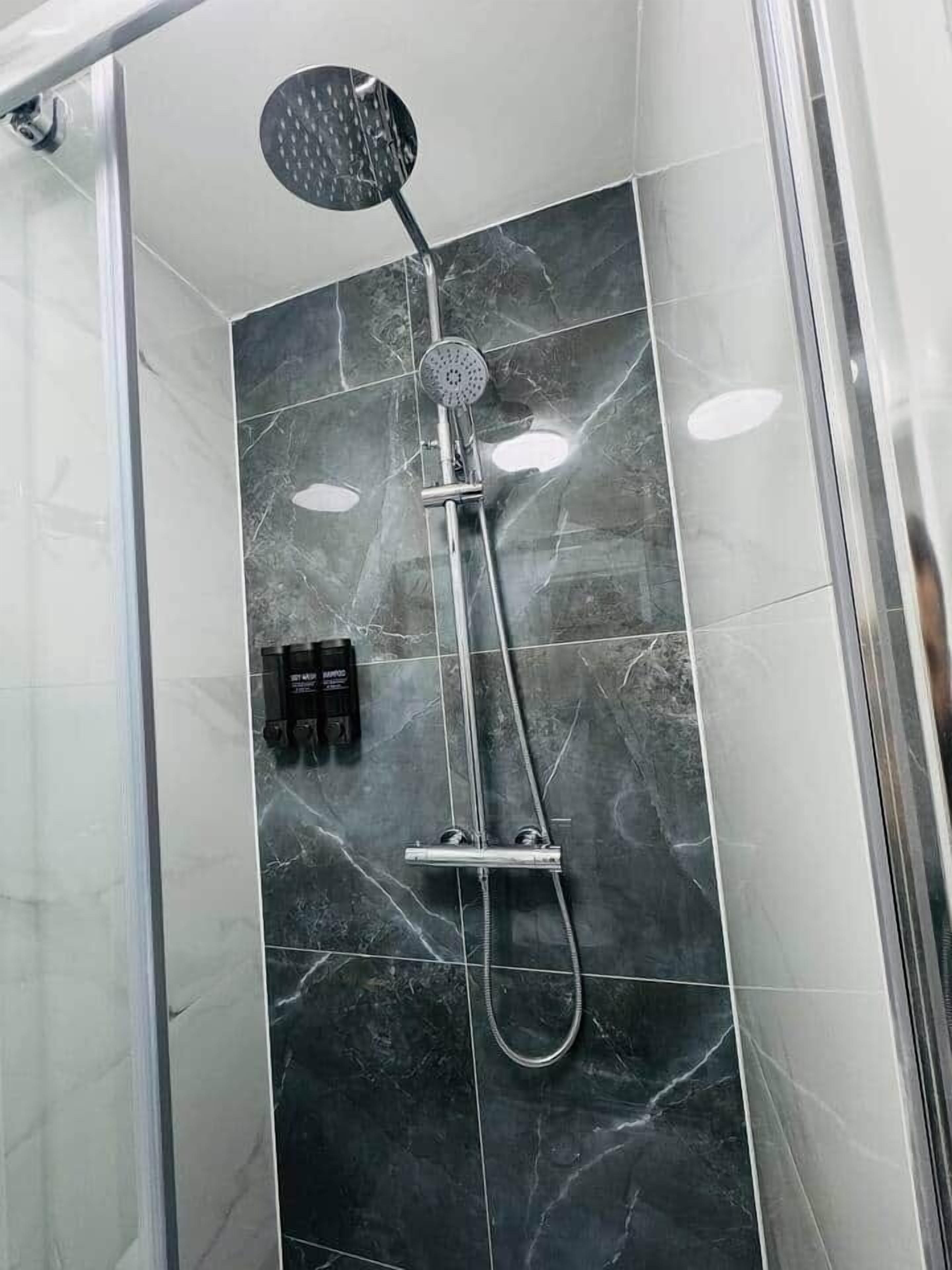 A shower with a handheld showerhead and a wall-mounted faucet.