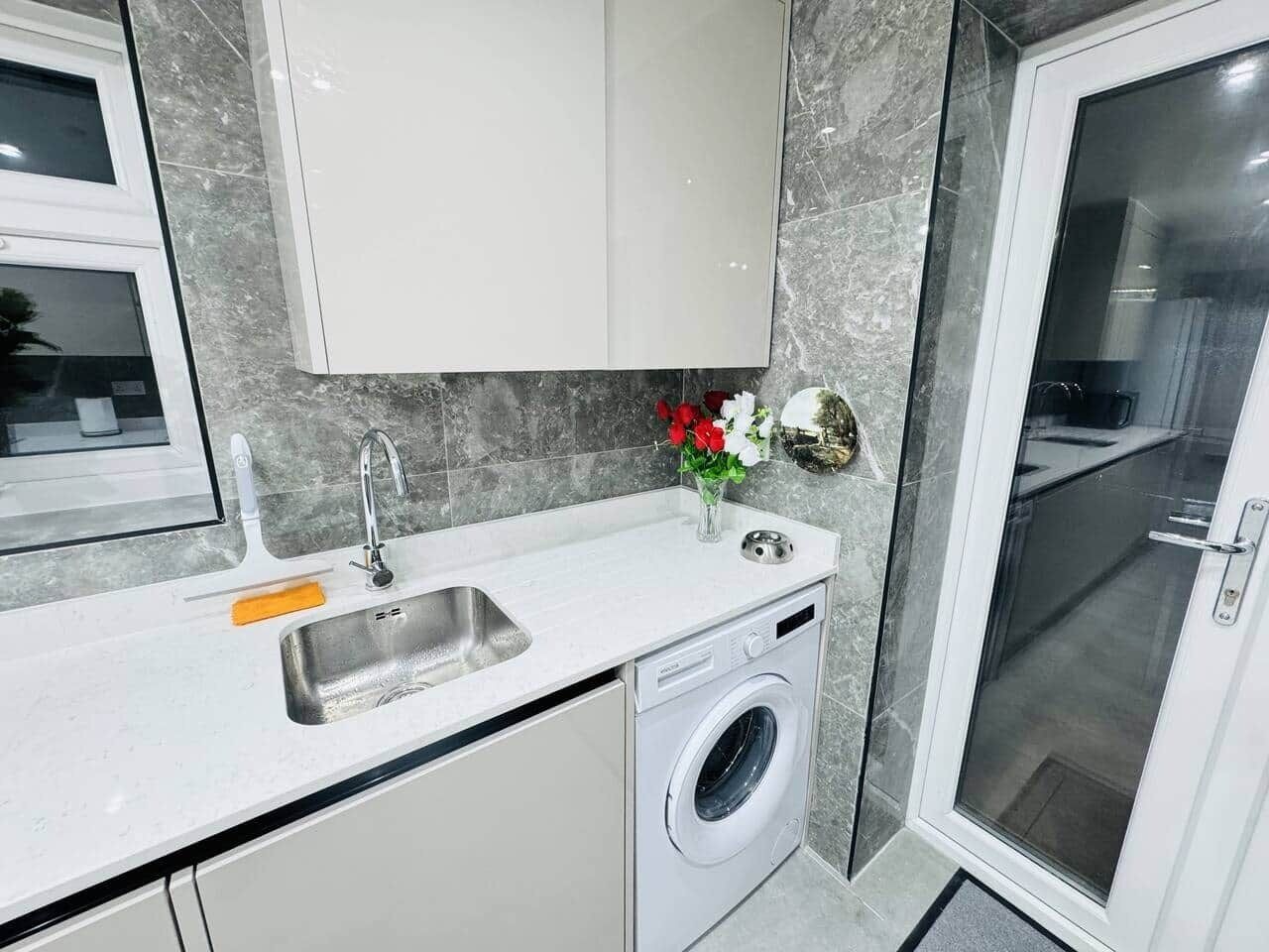 A compact kitchen with a built-in washing machine, a sink, and a small countertop.