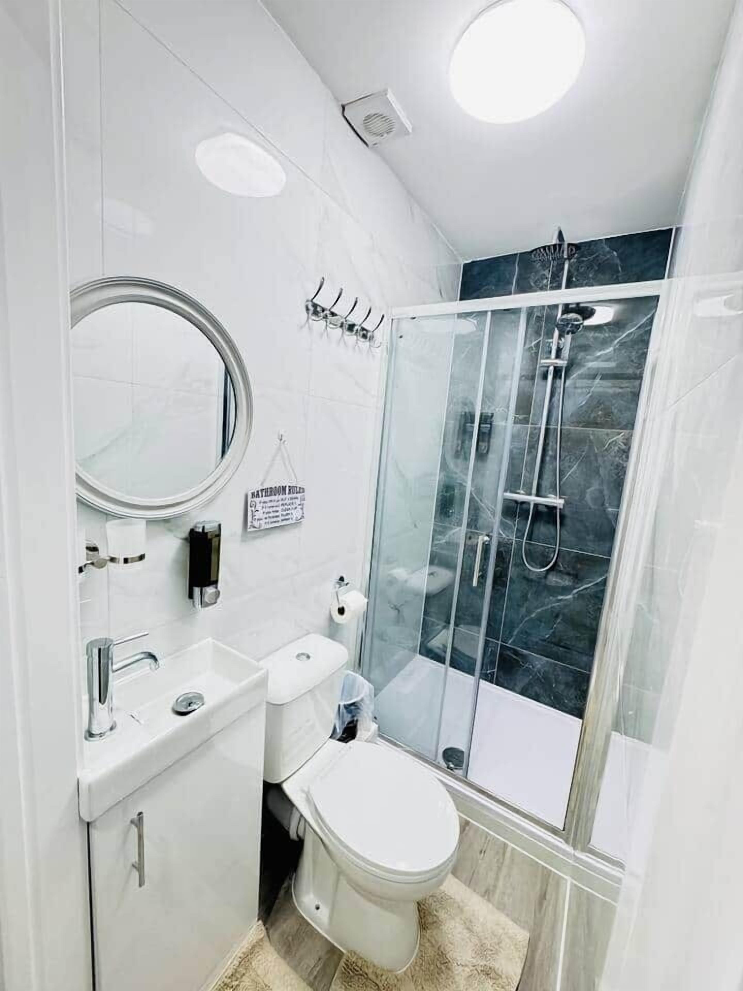 Un bagno moderno con toilette, lavabo, specchio e doccia.