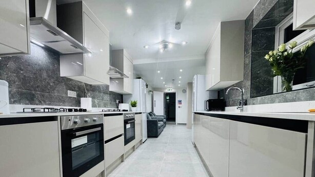 A modern kitchen with white cabinets, a black oven, and a marble backsplash. - Private En-Suite Room near Cardiff City Centre (Cardiff)