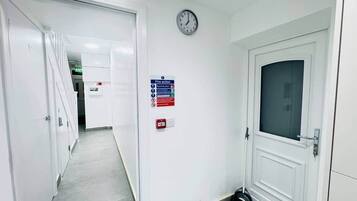 A hallway with white walls, a clock, a fire action sign, and an exit sign.