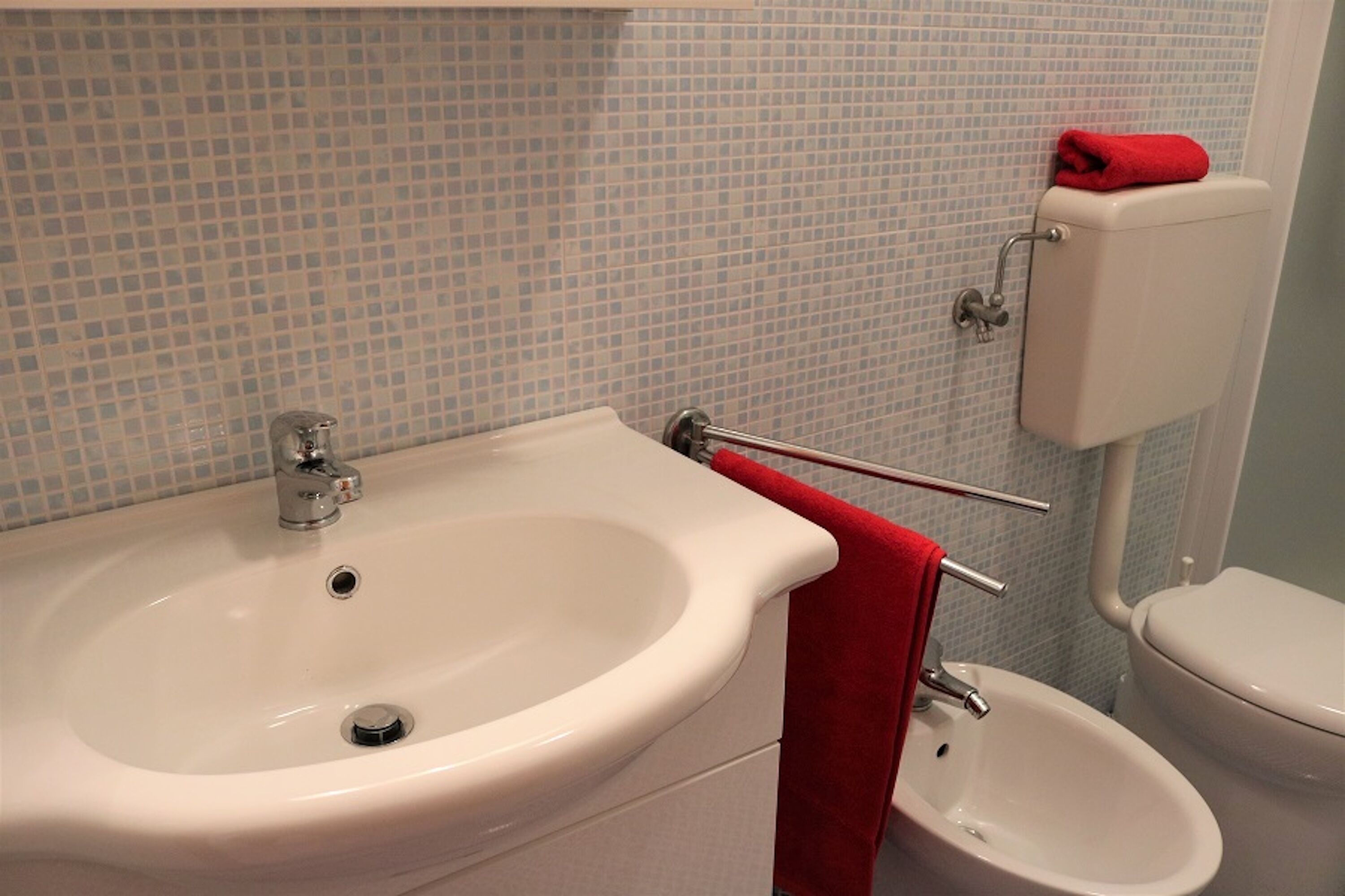 A bathroom with a white sink, a bidet, and a toilet.