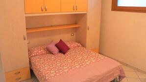 A bedroom with a bed, a wardrobe, and a window. - Lovely Flat With Patio (San Michele al Tagliamento)