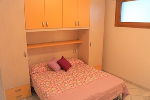 A bedroom with a bed, a wardrobe, and a window. - Lovely Flat With Patio (San Michele al Tagliamento)