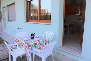 Zona pranzo con tavolo imbandito per quattro persone, circondato da sedie bianche, e una finestra sopra.