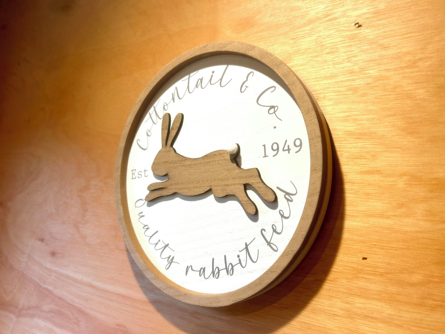 Une plaque en bois représentant la silhouette d’un lapin, avec un texte.