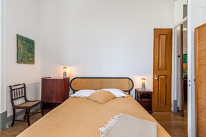 Ein Schlafzimmer mit einem Bett, einem Sessel, einem Schrank und einer Tür.