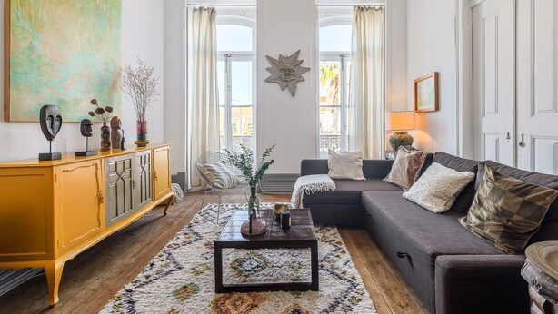 A living room with a sofa, a coffee table, a yellow cabinet, and a large abstract painting. - Apartment 'Victorian Beach House Luisa Todi' with Balcony and Wi-Fi (Setúbal)