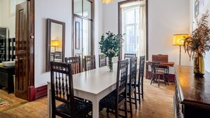 A dining area with a white table, wooden chairs, a vase with flowers, and a chandelier. - Apartment 'Victorian Beach House Luisa Todi' with Balcony and Wi-Fi (Setúbal)