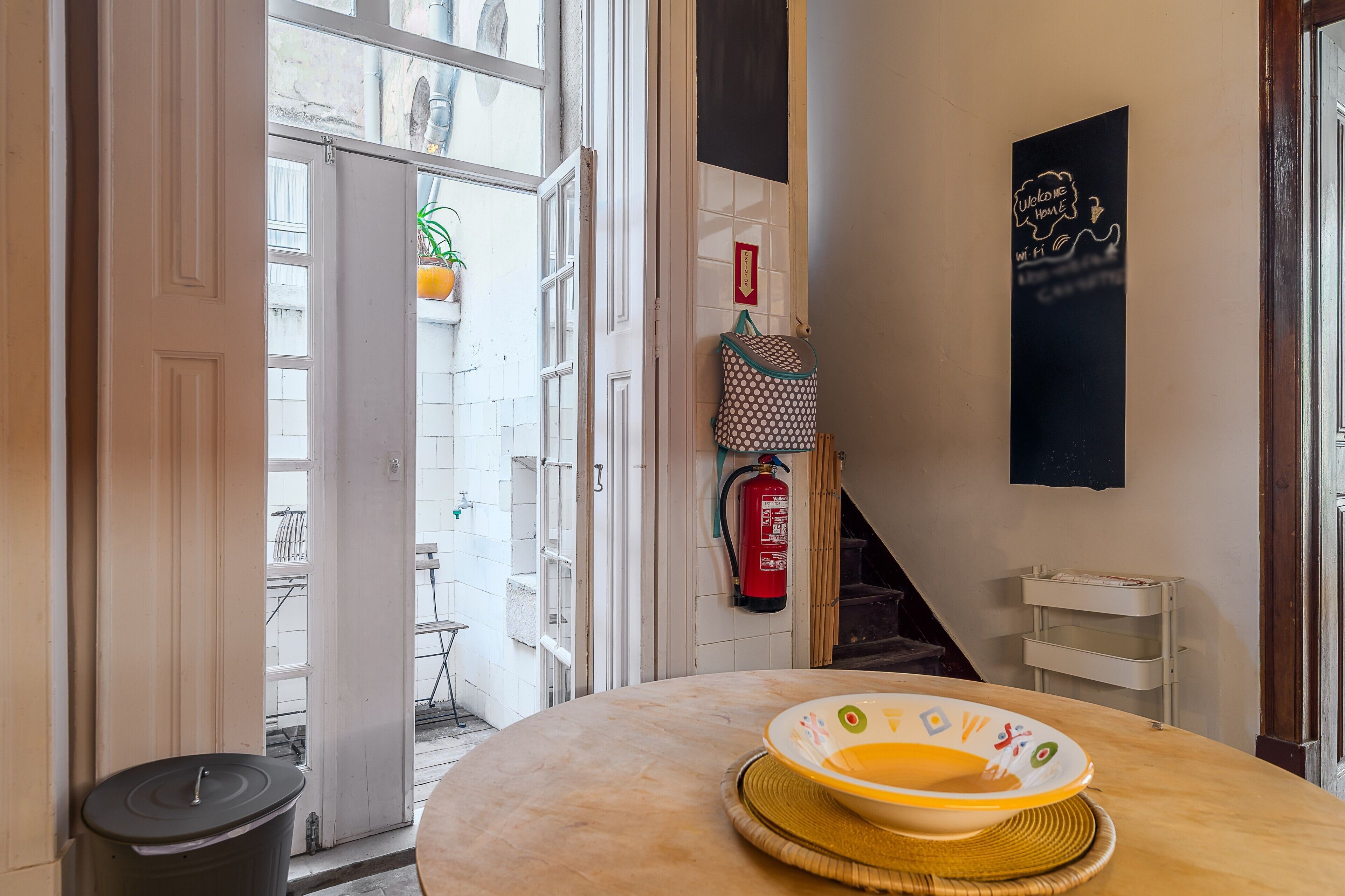 Une cuisine avec une table ronde, un extincteur et une pancarte indiquant « Bienvenue à la maison ».